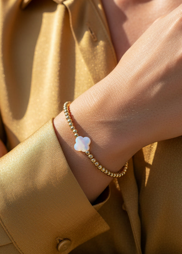Goud kralenarmbandje met een witte klaver